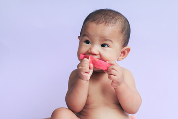 asian cute baby girl eating red dragon fruit. newborn baby on white background