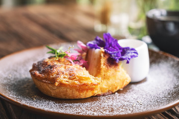A piece of coconut pie with a beautiful decoration and a cup of coffee on wooden table