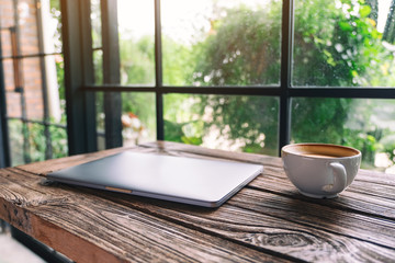 A single laptop computer with a coffee cup on wooden table