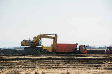 Fototapeta na wymiar excavator loading soil, sand in a dump truck