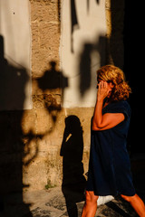 Syracuse, Sicily, Italy Pedestrians walk by the shadow of a street lamp in the late afternoon on Ortygia or Ortigia island.