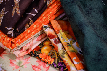 Assorted pile of fall colored fabric and bolts of cloth