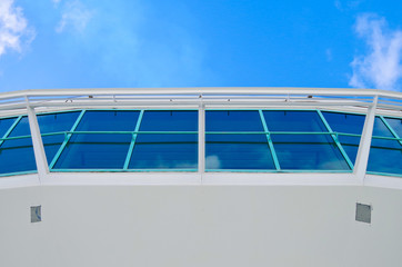 Weiße Bordwand mit Fensterfront von Kreuzfahrtschiff vor blauem Himmel