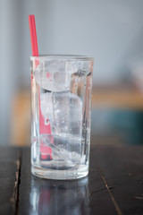 A transparent glass and ice with red straw drink