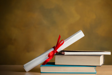 Scroll of certificate ,books,pen on wooden table with copy space