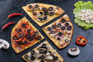 Assorted pizza slices. Margherita, pepperoni, four cheese pizza. Top view. Different types of pizza on the textured old wooden table.