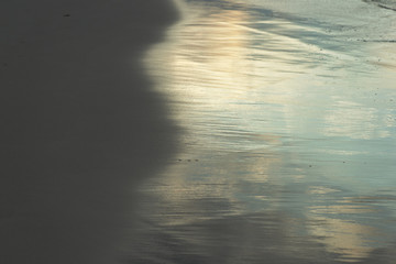 Wet sand on the beach lit by the evening sun closeup. Natural abstract background