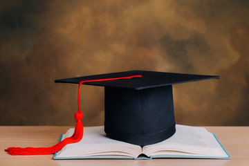 Graduation cap over open Books on wooden background.Education concept.Graduation day