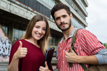 Two University students showing thumbs up