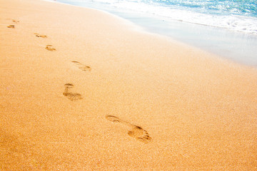 Fototapeta na wymiar Footprints from children's feet in the clear sea sand