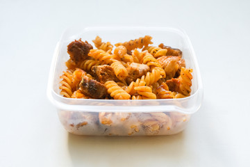 Fusilli pasta with meat bolognese tomato sauce. Business lunch in a plastic box container.