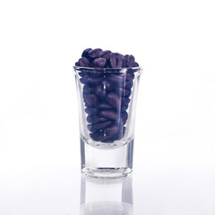 Fresh roasted beans in glassware on background.