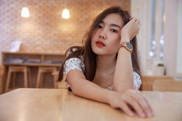 Asian woman relaxing to wait hot coffee latte art at coffee cafe .