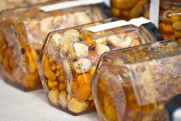 Lots of assorted honey on the table. Jars of sweets are sold at the fair. Honey with different kinds of nuts then dried fruits.