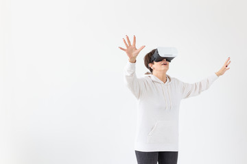 Positive pretty middle-aged woman in a white sweater watching a movie with glasses of virtual reality. The concept of futurism and new technologies.