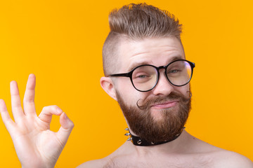 Positive funny hipster shirtless guy with a rocker collar shows ok on a yellow background. Concept...