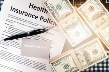 Obraz premium background of health insurance gold card member with pen on health insurance policy document and US bank note on table