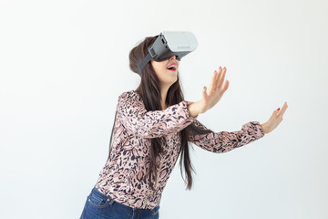Young woman watches a movie with glasses of virtual reality standing on a white background. The...