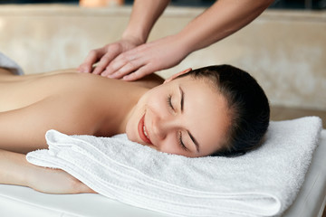 Fototapeta na wymiar Young woman enjoying massage in spa salon. Body care. Woman having massage in the spa salon