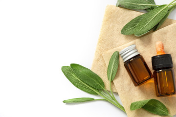Close up fresh green sage herb leaf with a bottle of essential oil on white background , herb essence concept