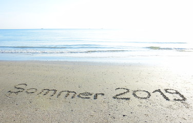 Text Sommer 2019 in den Sand geschrieben am Meer bei Sonnenaufgang