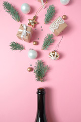 Champagne bottle with different christmas decoration on pink background. New year concept.