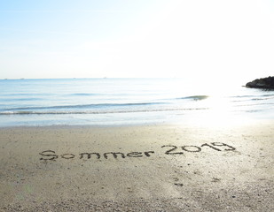 Sommer 2019 in den Sand geschrieben mit dem Hintergrund das Meer und der Sonnenaufgang