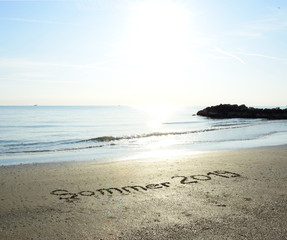 Sommer 2019 in den Sand geschrieben mit dem Hintergrund das Meer und der Sonnenaufgang