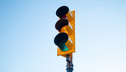 Green traffic light for cars, blue sky background