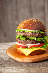 Tasty burger with cheese on wooden table