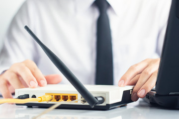Hand of network engineer checking modem beside has laptop on table, Network communication concept