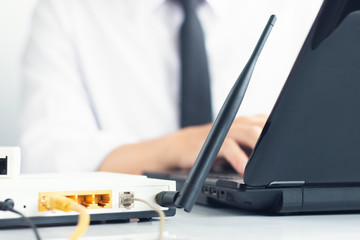 Hand of Network engineer typing on laptop keyboard beside has modem and LAN cable on table, Network...