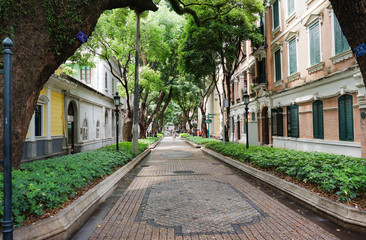 Corridor between buildings in China On the way there are green trees around. The building is ancient.