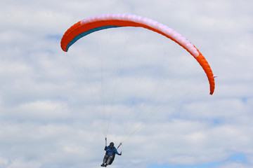 Paraglider flying orange wing
