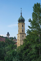Fototapeta na wymiar Mur river, the Franciscan Church tower and the famous clock tower (Grazer Uhrturm) in the background, in the centre of the city of Graz, Styria region, Austria