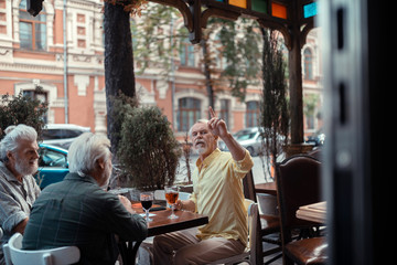Man calling for waiter while sitting outside pub