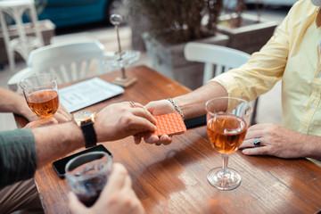 Man wearing watch taking card while playing with friends
