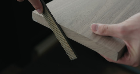 Fototapeta premium woodworker hand sanding walnut board with file