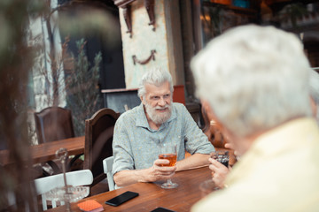 Bearded grey-haired man drinking alcohol with friends