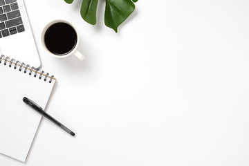 Office desk with laptop, blank notepad, pen coffee and green leaf. flat lay with copy space.