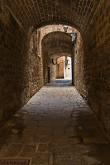 Fototapeta na wymiar Architectural details of medieval stone and brick houses in a narrow passages at Volterra, Tuscany, Italy