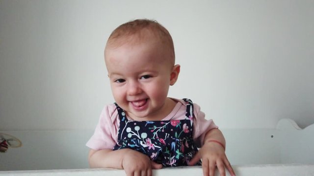 Cule baby laughing and having fun, standing in crib. Happy baby. Baby emotions. Baby smile.