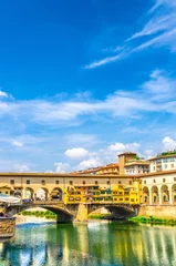 Deurstickers Ponte Vecchio stone bridge with colourful buildings houses over Arno River blue reflecting water in historical centre of Florence city, blue sky white clouds, vertical orientation, Tuscany, Italy © Aliaksandr