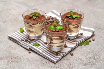Classic tiramisu dessert in a glass on kitchen towel on concrete background