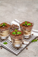 Classic tiramisu dessert in a glass on kitchen towel on concrete background