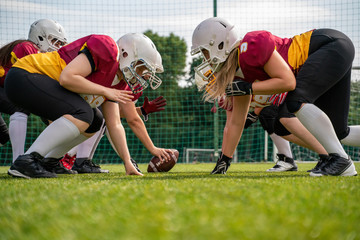 Photo of athletes wearing helmets playing american football on sports field