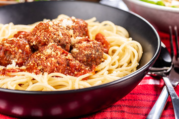 Traditional Italian spaghetti and meatballs in a round bowl on a red tablecloth