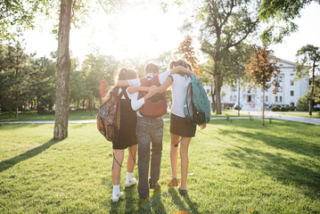 school friends a boy and two girls with school backpacks on their backs walk after class