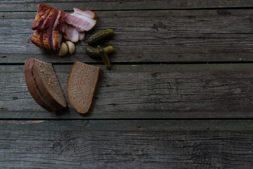 Snacks, bacon, pickled cucumbers on wooden background