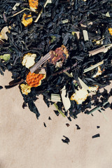 A close-up of dry  tea leaves and dry fruits. Black tea leaves background. Abstract food textures. A fruit tea for breakfast. Close up, top view.